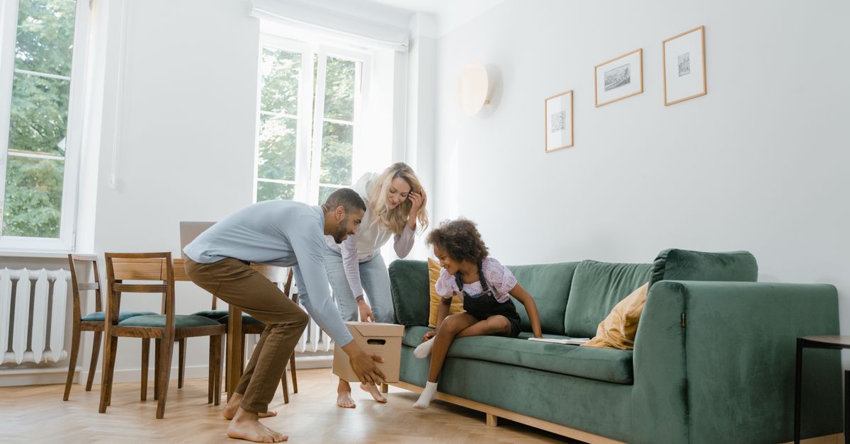 Parents and child unpacking a box in a living room, representing a practical and child-focused move plan.