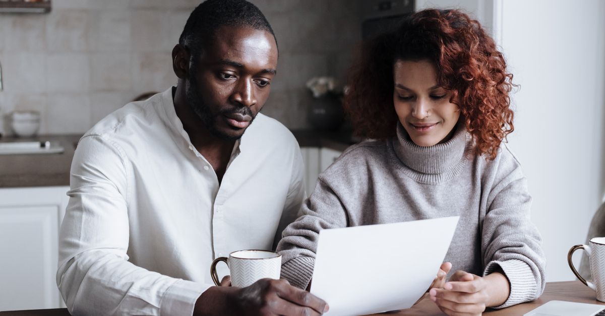 Couple reviewing paperwork together at a bright kitchen table, representing practical family planning and financial decisions.